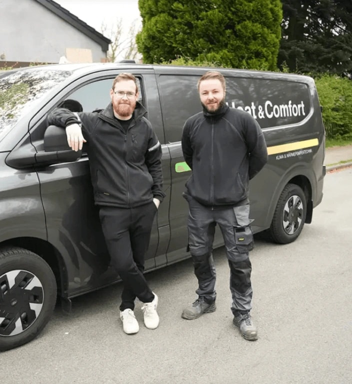Zwei Heizungs- und Klimatechniker von Heat & Comfort vor dem Firmenwagen