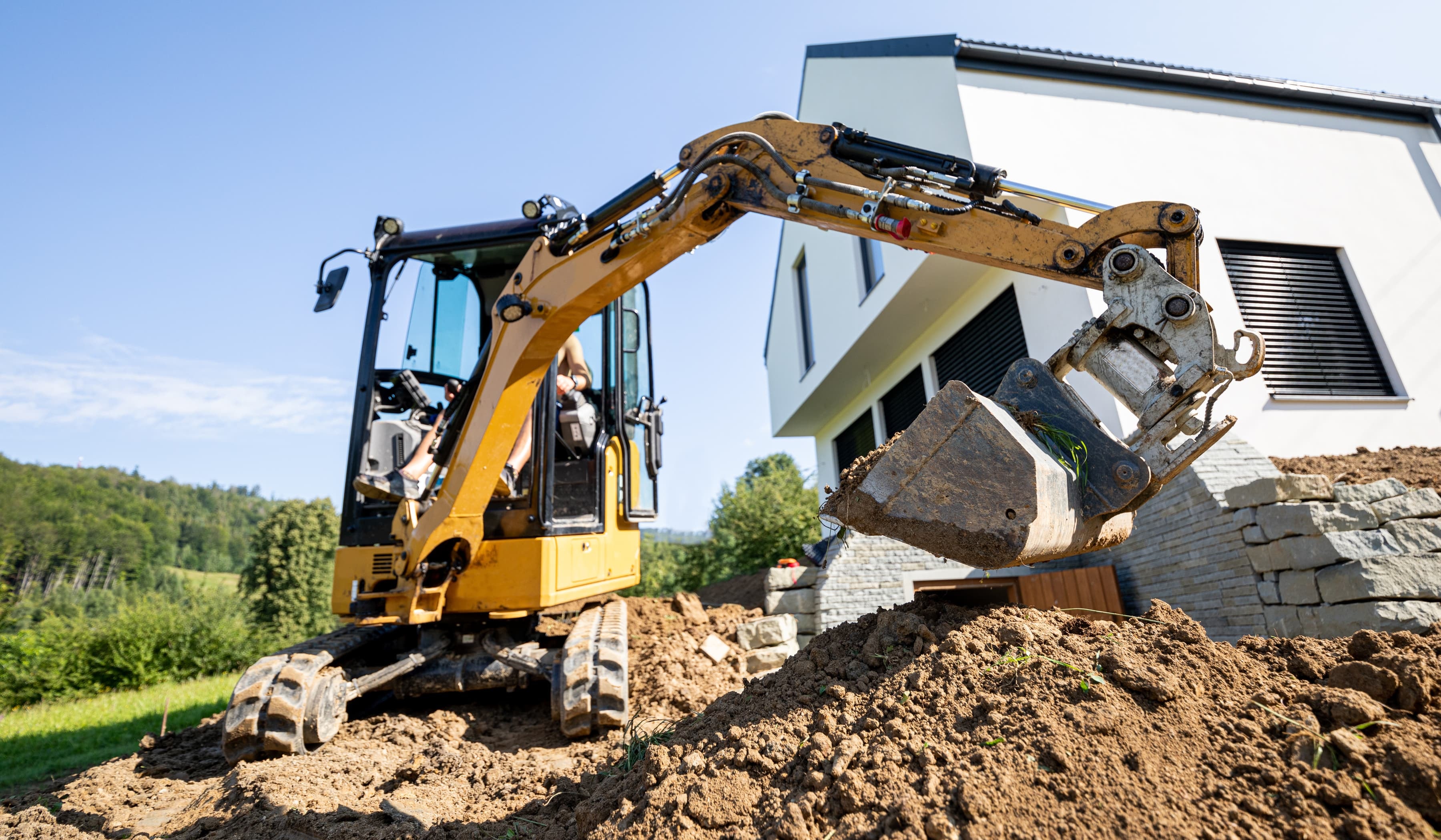 Minibagger bei Erdarbeiten auf einer Baustelle vor einem modernen Neubau
