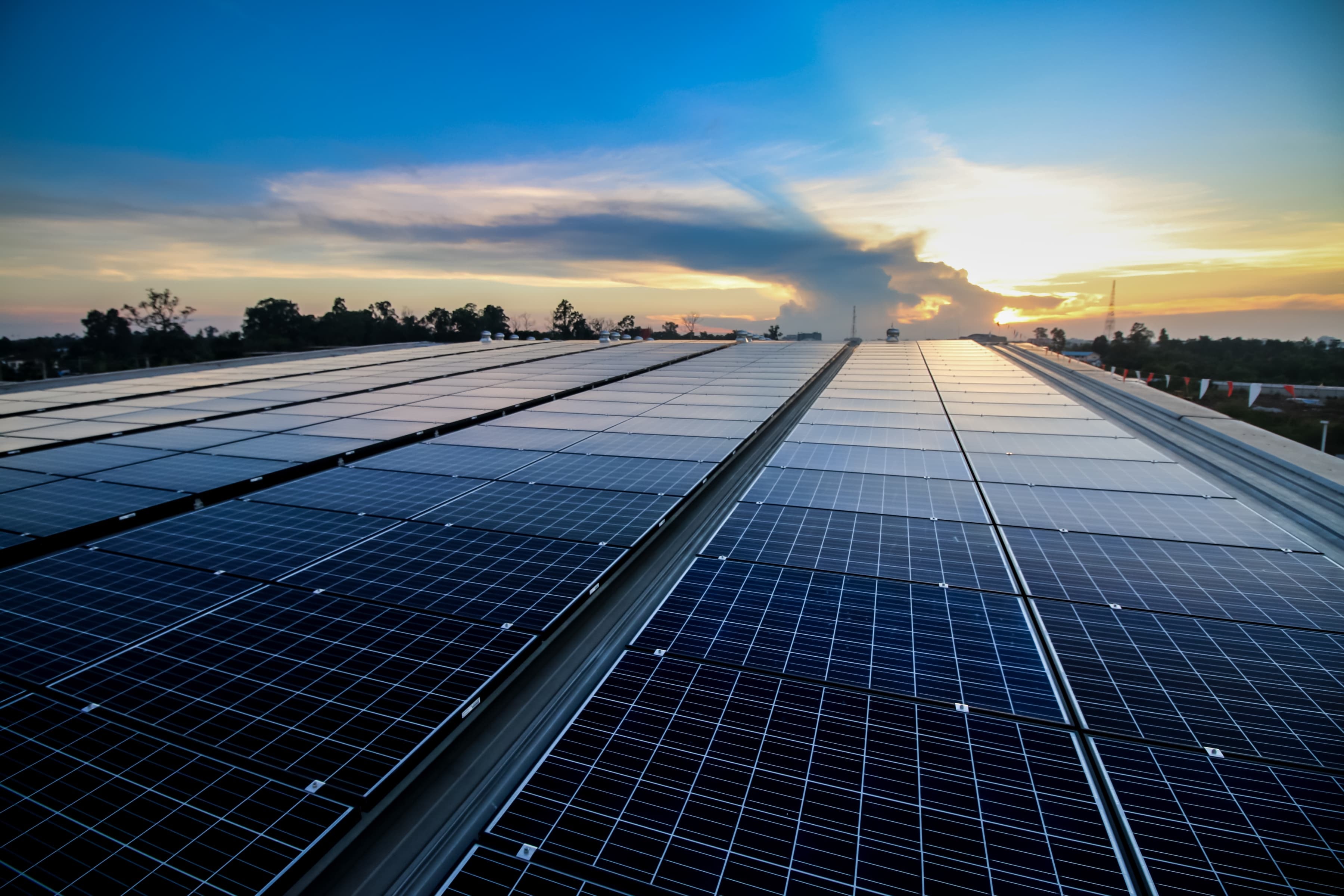 Photovoltaikanlage auf Industriedach bei Sonnenuntergang zur Erzeugung von Solarstrom