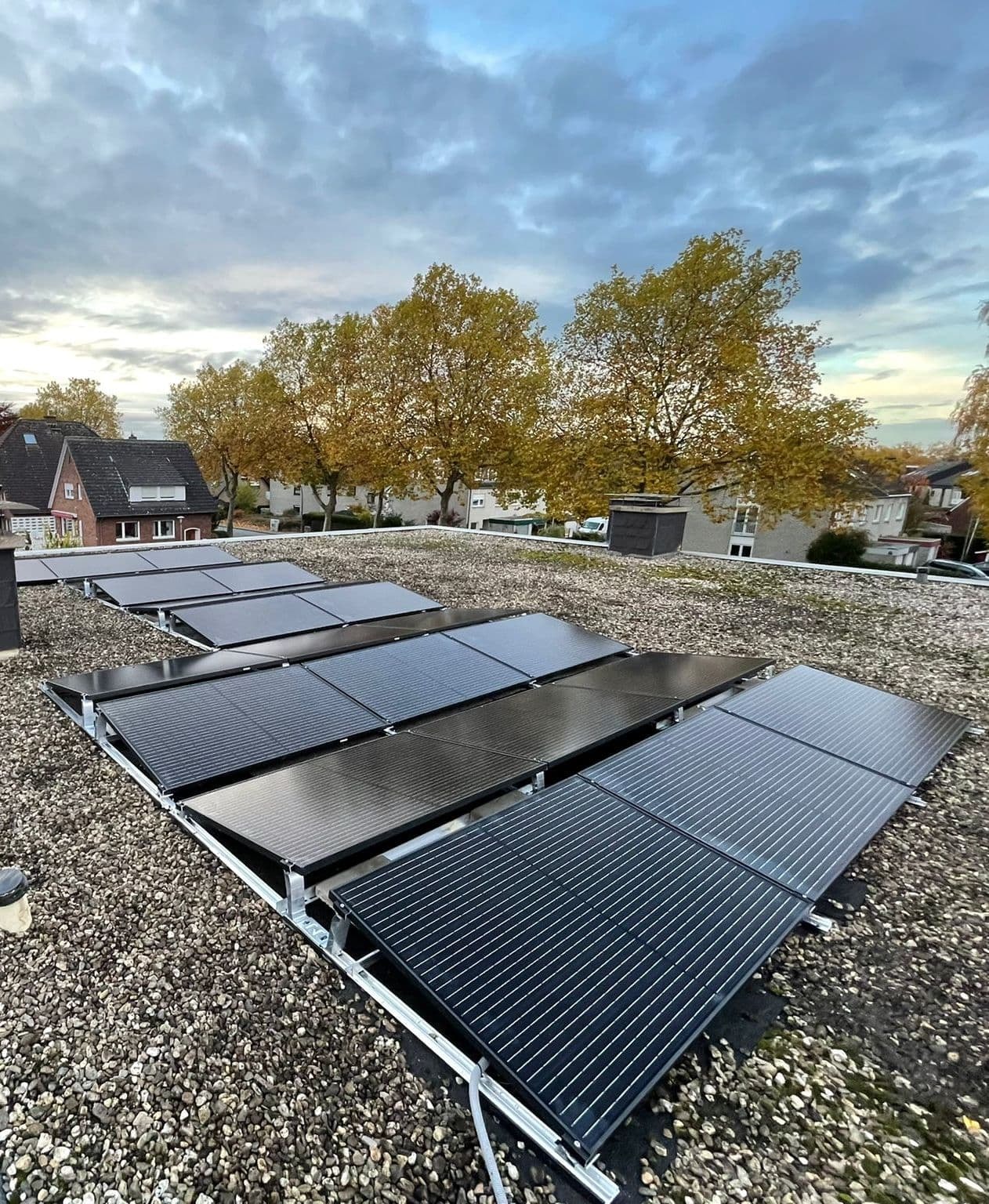 Photovoltaikanlage auf Flachdach mit Aufständerung und schwarzen Solarmodulen im Wohngebiet